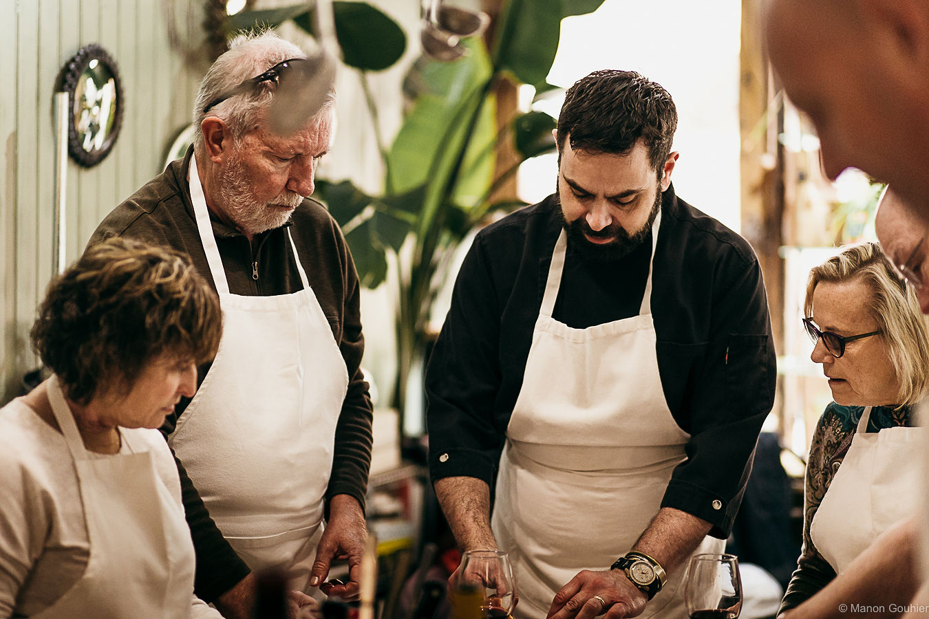 Travelers in white aprons cooking together with a chef in a Lyon kitchen